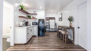 A modern kitchen with white cabinets, a stainless steel refrigerator, and wooden flooring. - Chic Yosemite Escape: King Suite w/ Plush Comforts (Oakhurst)