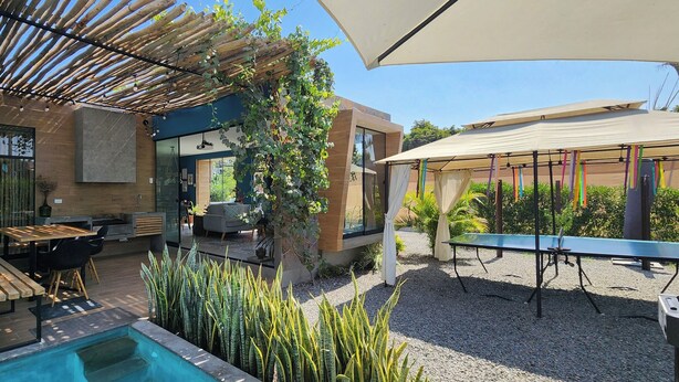 Eine moderne Außenpatio mit Pool, Steinmauern und einer Pergola.