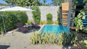Ein Garten mit Swimmingpool, Liegestühlen und einem Tisch unter einem Sonnensegel.