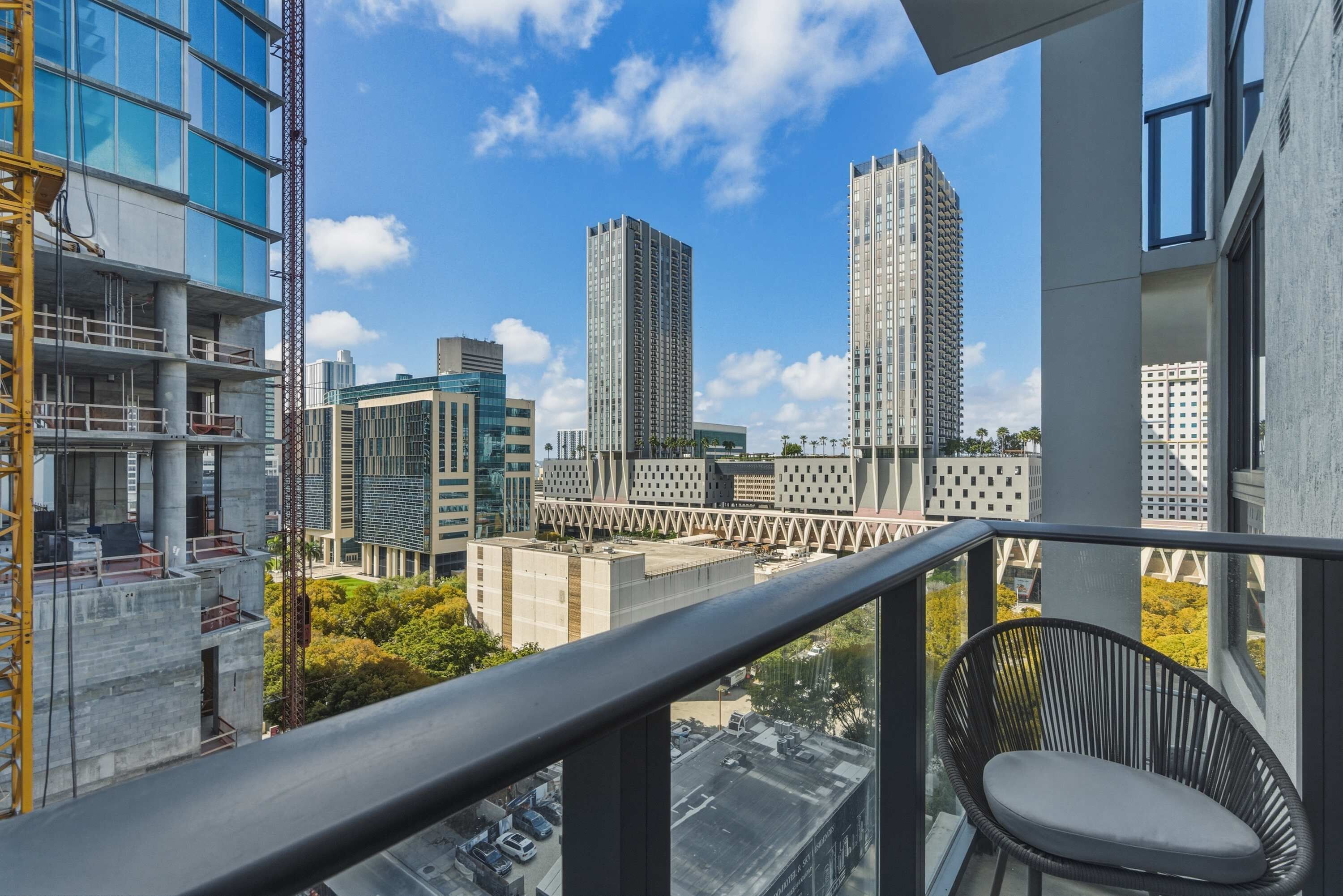 Een balkon met uitzicht op moderne hoogbouw en een bouwkraan.