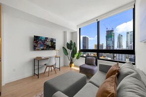 Ein modernes Wohnzimmer mit großem Fenster, einem Schreibtisch, einer bequemen Couch und einem Blumentopf.