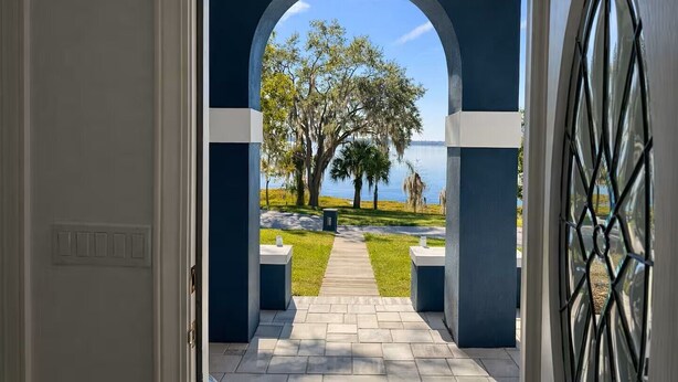 Un arco de entrada que da a un sendero con vistas a un lago y árboles.