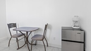 A kitchenette with a stainless steel refrigerator, a coffee maker, and two chairs with a coffee cup design.