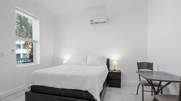 A bedroom with a bed, bedside tables, a desk, and a chair.