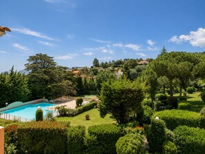 A pool surrounded by well-maintained lawns and trees, with a view of houses in the background. - Spacious 3-room apartment with a terrace – Quiet apartment complex with a pool (Mandelieu-la-Napoule)