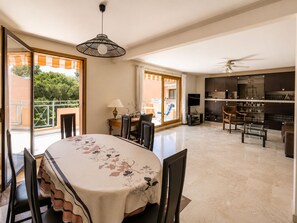 A spacious living area with a dining table, chairs, a sofa, and a ceiling fan. - Spacious 3-room apartment with a terrace – Quiet apartment complex with a pool (Mandelieu-la-Napoule)