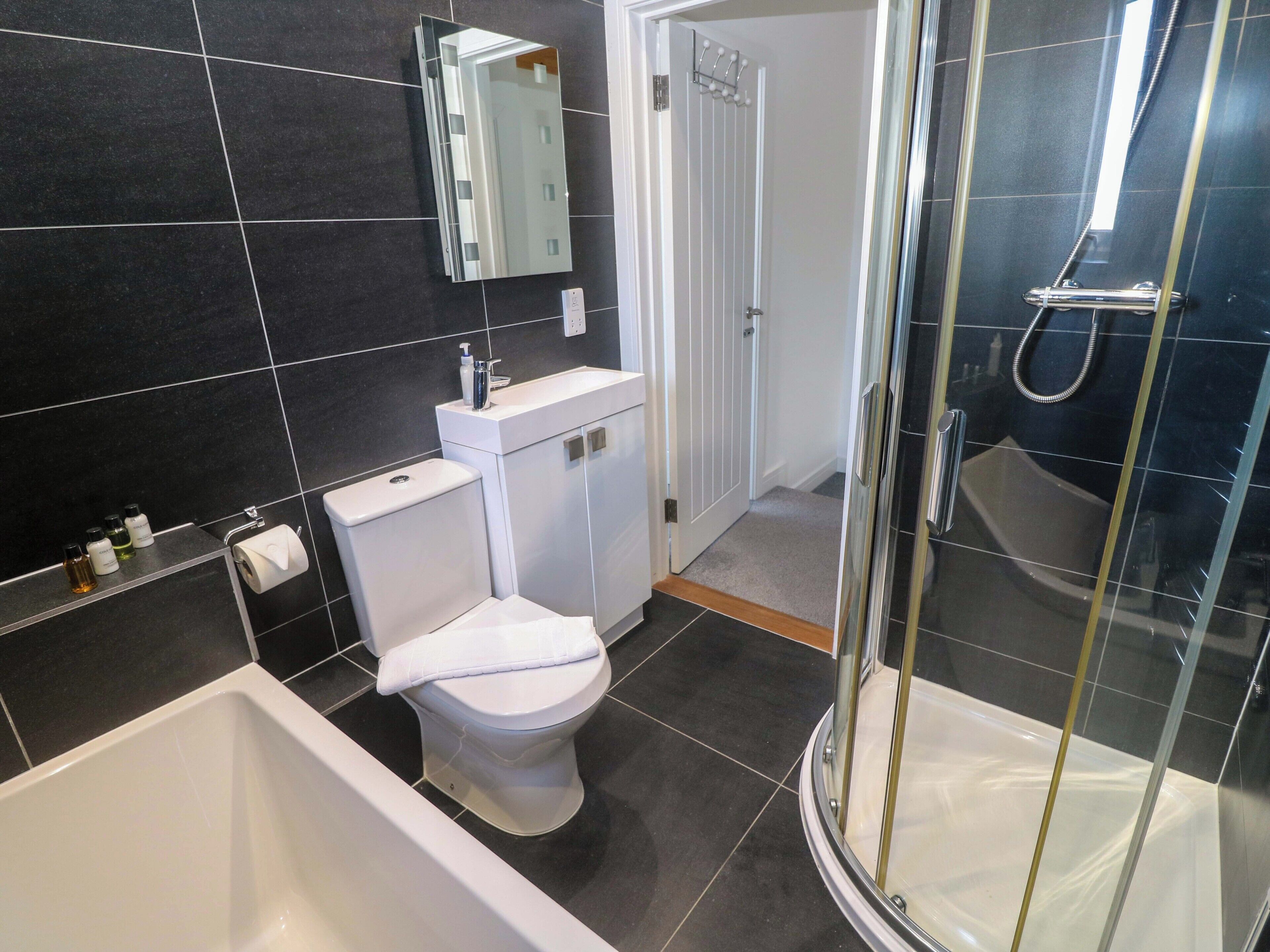 Ein modernes Badezimmer mit Toilette, Waschbecken, Spiegel und Dusche.