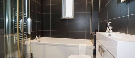 Un baño moderno con bañera, inodoro y cabina de ducha de vidrio.