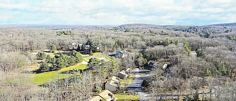 A residential area with houses, a golf course, and a hilly landscape.