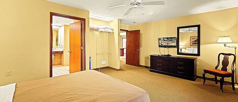 A hotel room with a bed, a dresser, a chair, a ceiling fan, and a mirror.