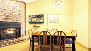 Comedor con chimenea de ladrillo, mesa de madera y sillas.