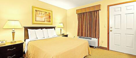 A hotel room with a bed, two bedside tables with lamps, a painting on the wall, a window with curtains, and a door.