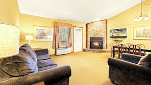 Ein Wohnzimmer mit Kamin, Esstisch und zwei Sofas.