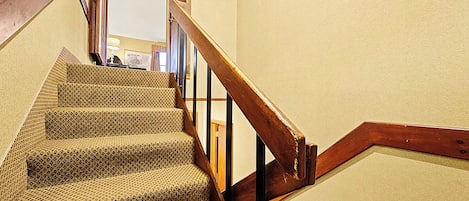 A staircase with a wooden handrail and carpeted steps.