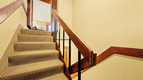 Una escalera con barandilla de madera y peldaños alfombrados.