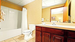 Un baño con bañera, inodoro y tocador con espejo.