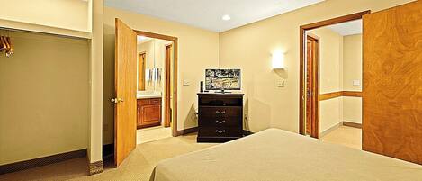 A hotel room with a bed, a dresser, a mirror, and a television.