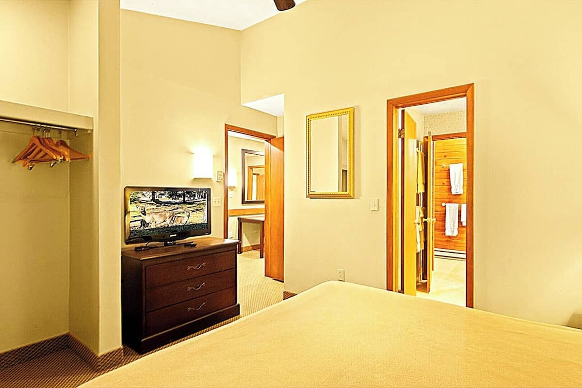 Una camera d'albergo con un letto, una cassettiera, un televisore, uno specchio e una lampada.
