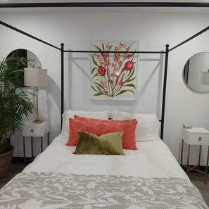 A bedroom with a four-poster bed, a potted plant, a mirror, and a framed botanical print on the wall. - New Gated 2BR Near Medical Center, NRG & Downtown (Houston)