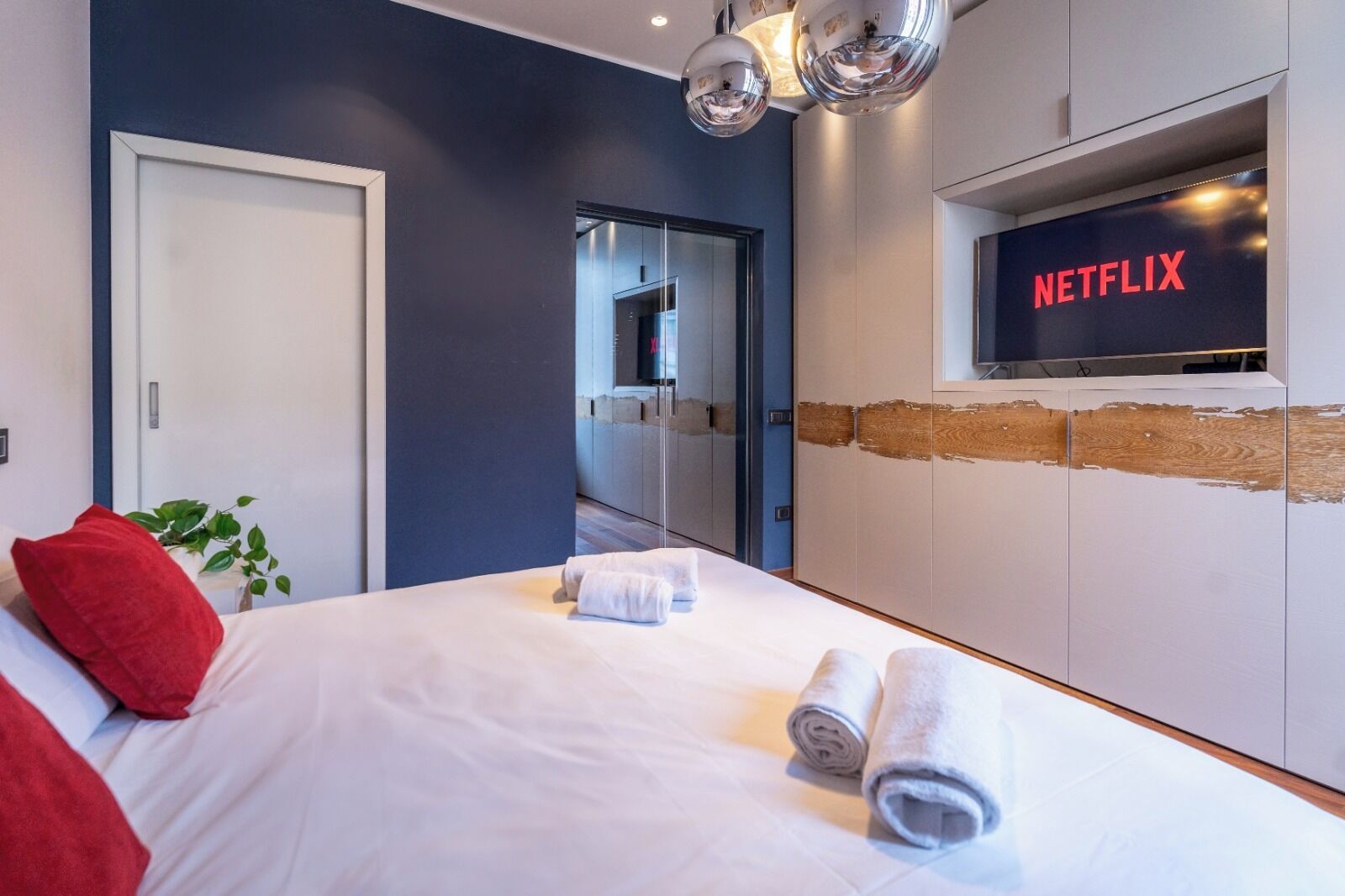 Una camera d'hotel moderna con un letto, una TV a parete e un'uscita verso il bagno.