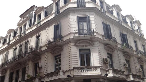 Un edificio de esquina con estilo arquitectónico clásico, que presenta varios balcones y ventanas amplias.
