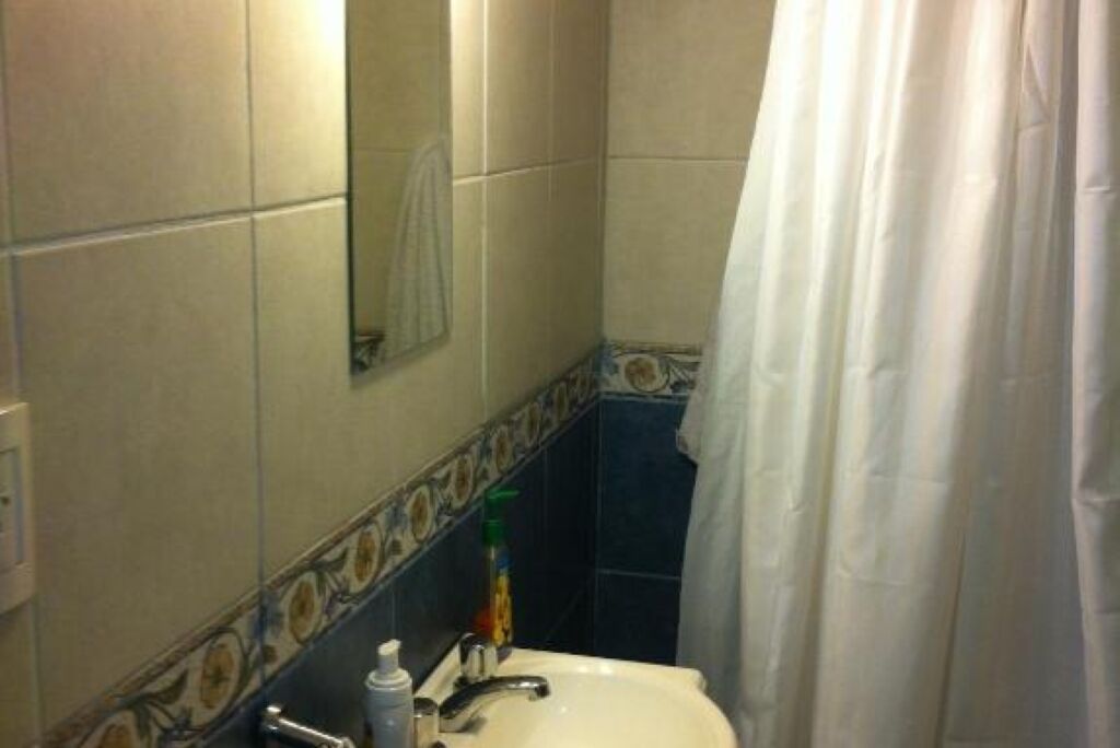Ein Badezimmer mit Waschbecken, Spiegel und Duschvorhang.