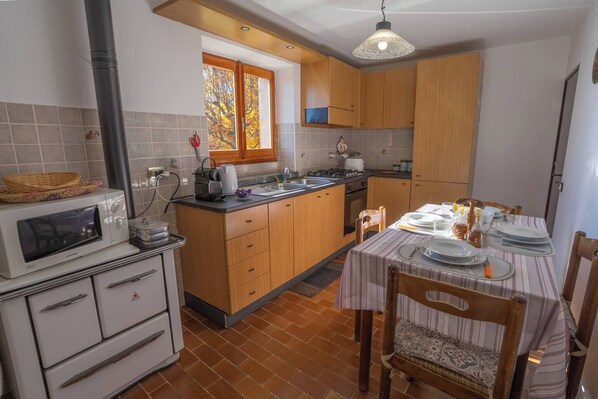 A kitchen with wooden cabinets, a built-in oven, a microwave, and a dining area with a table set for two.
