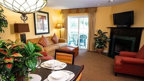 A living room with a dining table set for two, a sofa, a red armchair, a fireplace, and a television on the wall. - 4th of July Week! - Williamsburg, ONLY => 26 Jun - 3 Jul 2027, Sleeps 12/4Br/4Ba (Williamsburg)