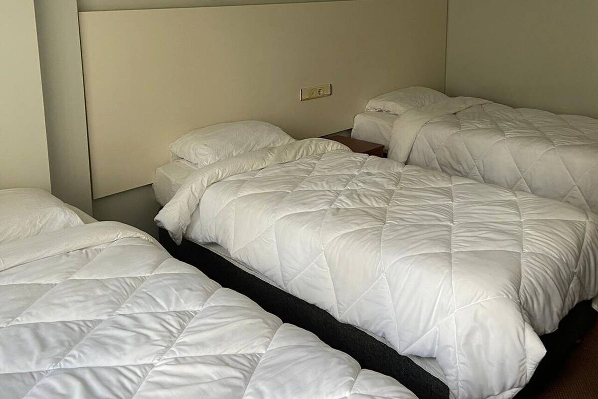 A hotel room with two beds, a headboard, and a light fixture.