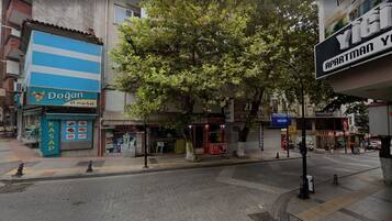 Vista de calle con un edificio azul y blanco identificado como 'Dogan et market' y un edificio verde con el rótulo 'KOR'.