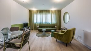 Una sala moderna con una mesa de comedor de vidrio, un sofá y un sillón verde.