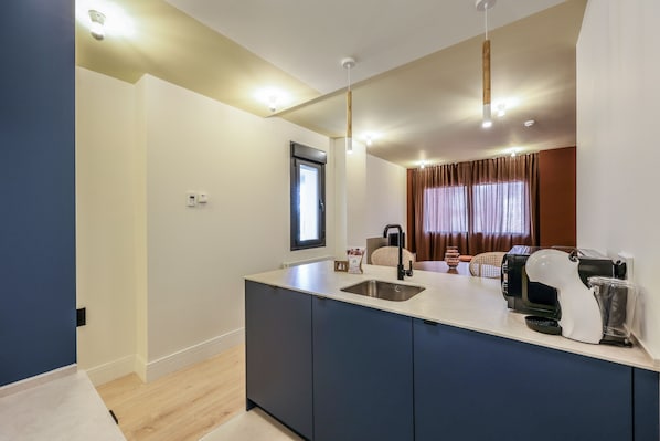 Una cocina moderna con una isla central, electrodomésticos integrados y un ventanal con cortinas.