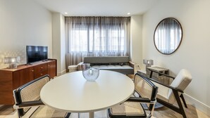Una sala moderna con una mesa de comedor redonda, un sofá y un televisor sobre un mueble de madera.