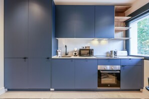Une cuisine moderne avec des meubles de couleur bleu foncé, un four à micro-ondes, un grille-pain et un four traditionnel.
