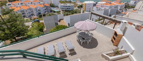 A rooftop terrace with outdoor seating and a view of the sea.