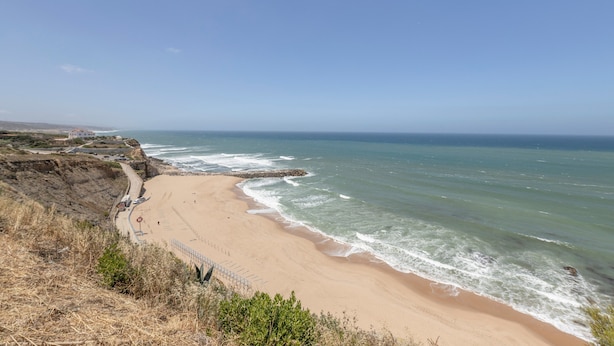 A coastal beach with a rocky cliff, a sandy shoreline, and a clear sky. - Holiday Home 'Ocean Villa Ericeira' with Sea View, Private Terrace and Wi-Fi (Ericeira)