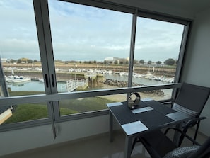 Ein Zimmer mit großem Fenster mit Blick auf eine Marina, wo Boote und eine Rasenfläche liegen.