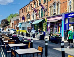 A street with outdoor seating, a bar, and a shop with a sign that says 'TAKE AWAY'. - Luxury Holiday Gateway in a Popular Trendy hotspot (Merseyside)