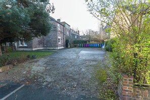 A residential street with houses, a driveway, and a row of colorful bins. - Luxurious 2BR Apartment| Free Parking | Lark Lane (Merseyside)