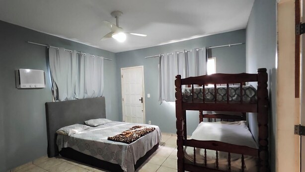 Un dormitorio con una cama individual, una litera, un ventilador de techo y una puerta.