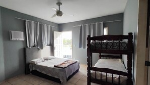 Un dormitorio con una cama individual, ventilador de techo y ventana con cortinas.