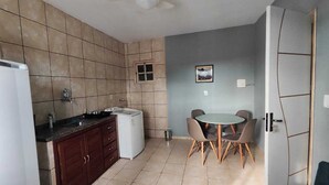 Una cocina compacta equipada con refrigerador, lavadora y comedor con mesa y sillas.