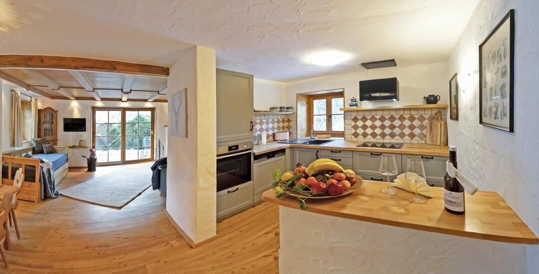 Une cuisine spacieuse avec un plancher en bois, un coin repas avec une table et des chaises, et une grande fenêtre qui laisse entrer la lumière naturelle.