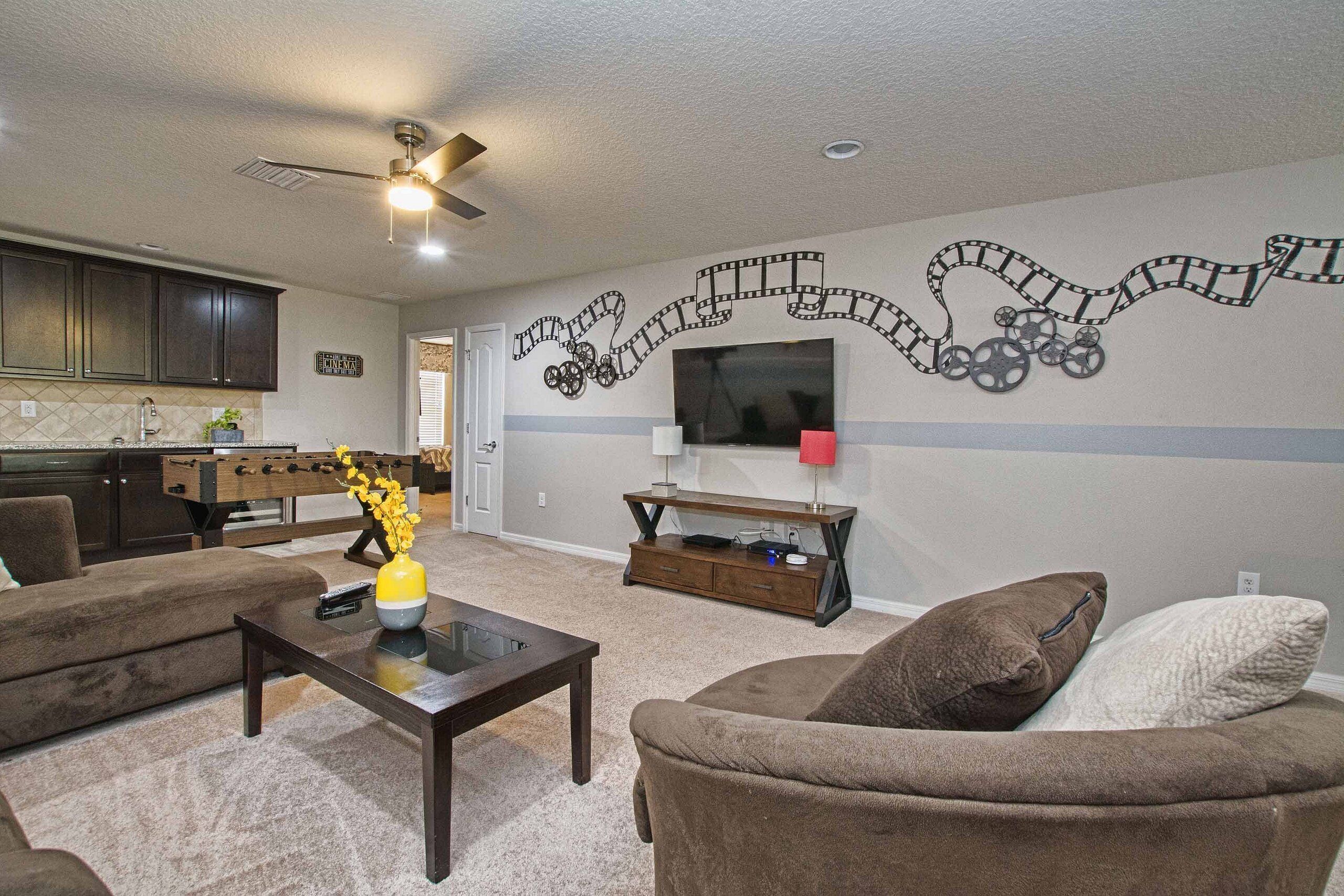 A living room with a sofa, coffee table, and a TV on the wall.