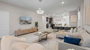 Een moderne woonkamer met een bank, salontafel en eethoek.