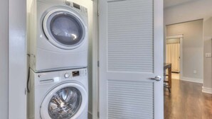 A laundry room with two stacked front-loading washing machines and a closed door.