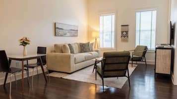 A modern living room with a sofa, chairs, a dining table, and a TV.