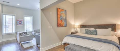 Un dormitorio con una cama grande, una mesita de noche, una lámpara y un cuadro en la pared.