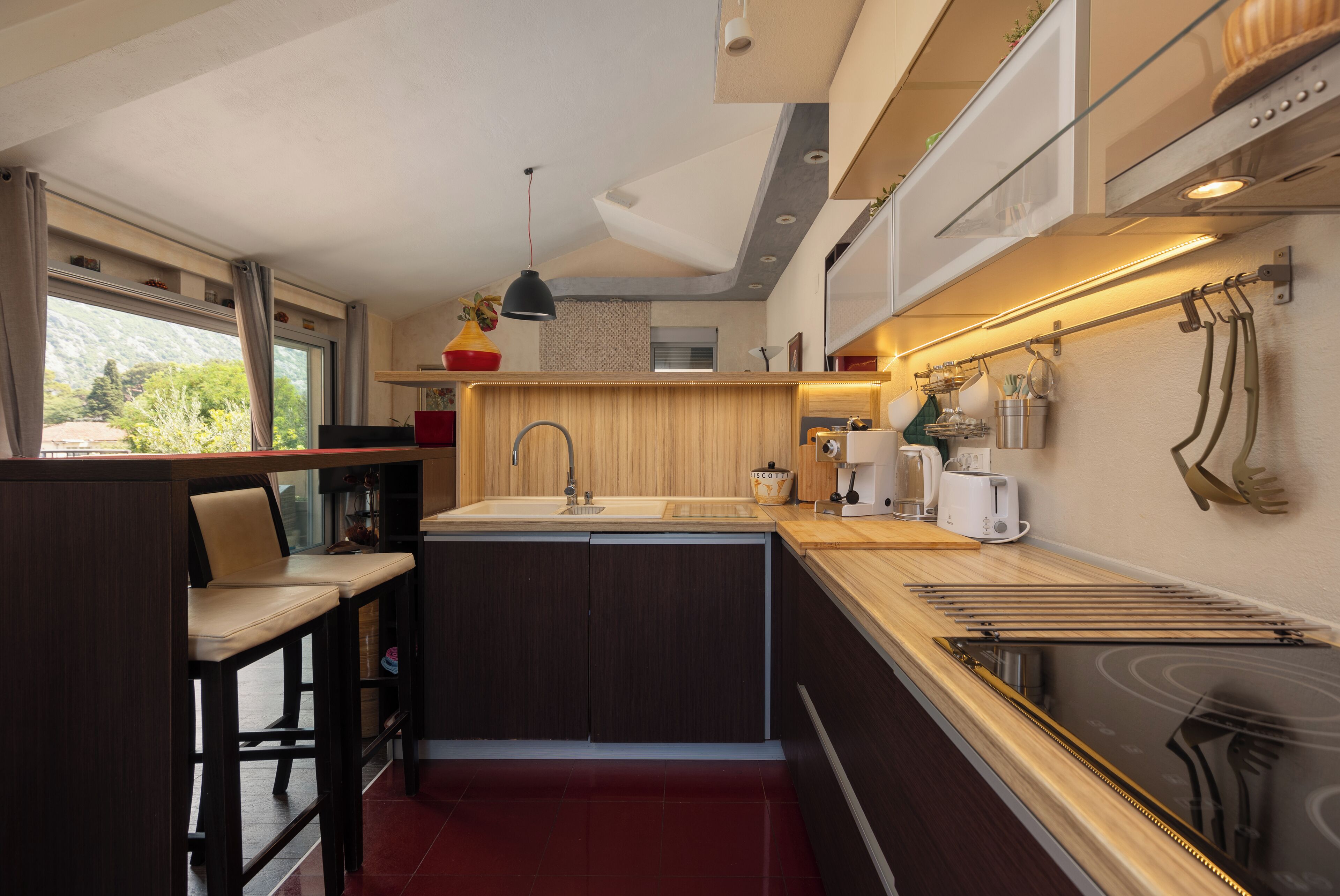 Una cocina compacta con una isla central, taburetes de bar, un fregadero y una estufa.