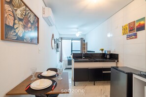 A modern kitchen with a central island, a dining area with a table set for two, and a large framed artwork on the wall. - Your Perfect Stay in Joao Pessoa, 220m From the sea - Rsks (João Pessoa)